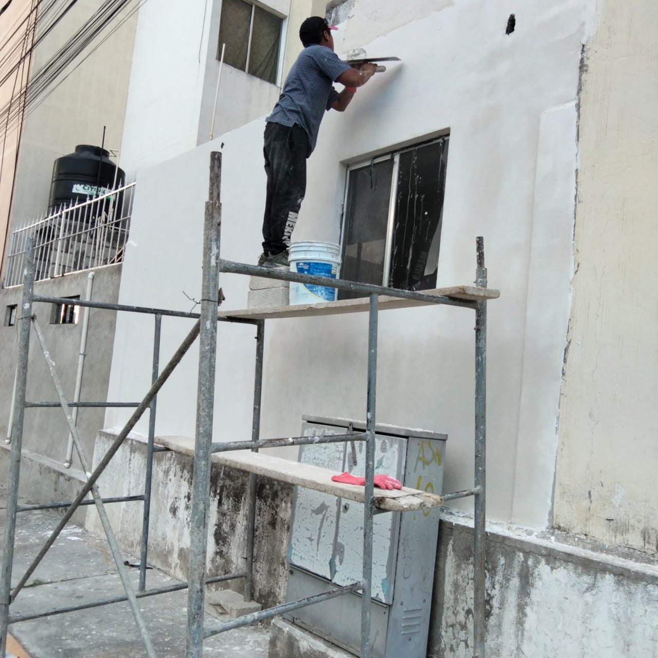 Técnico dando acabado de pintura en fachada